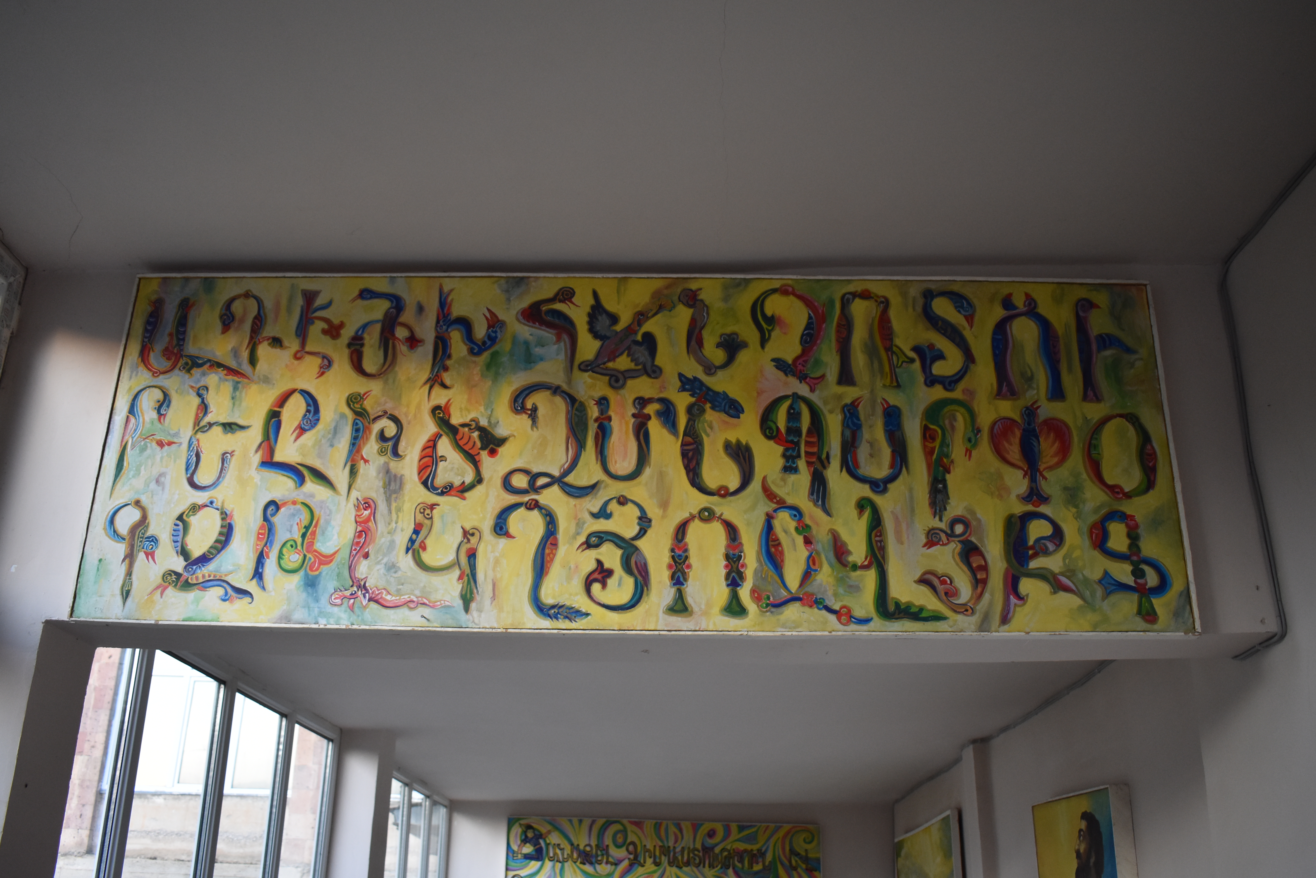 A colorful Armenian alphabet mural above a doorway in a public school