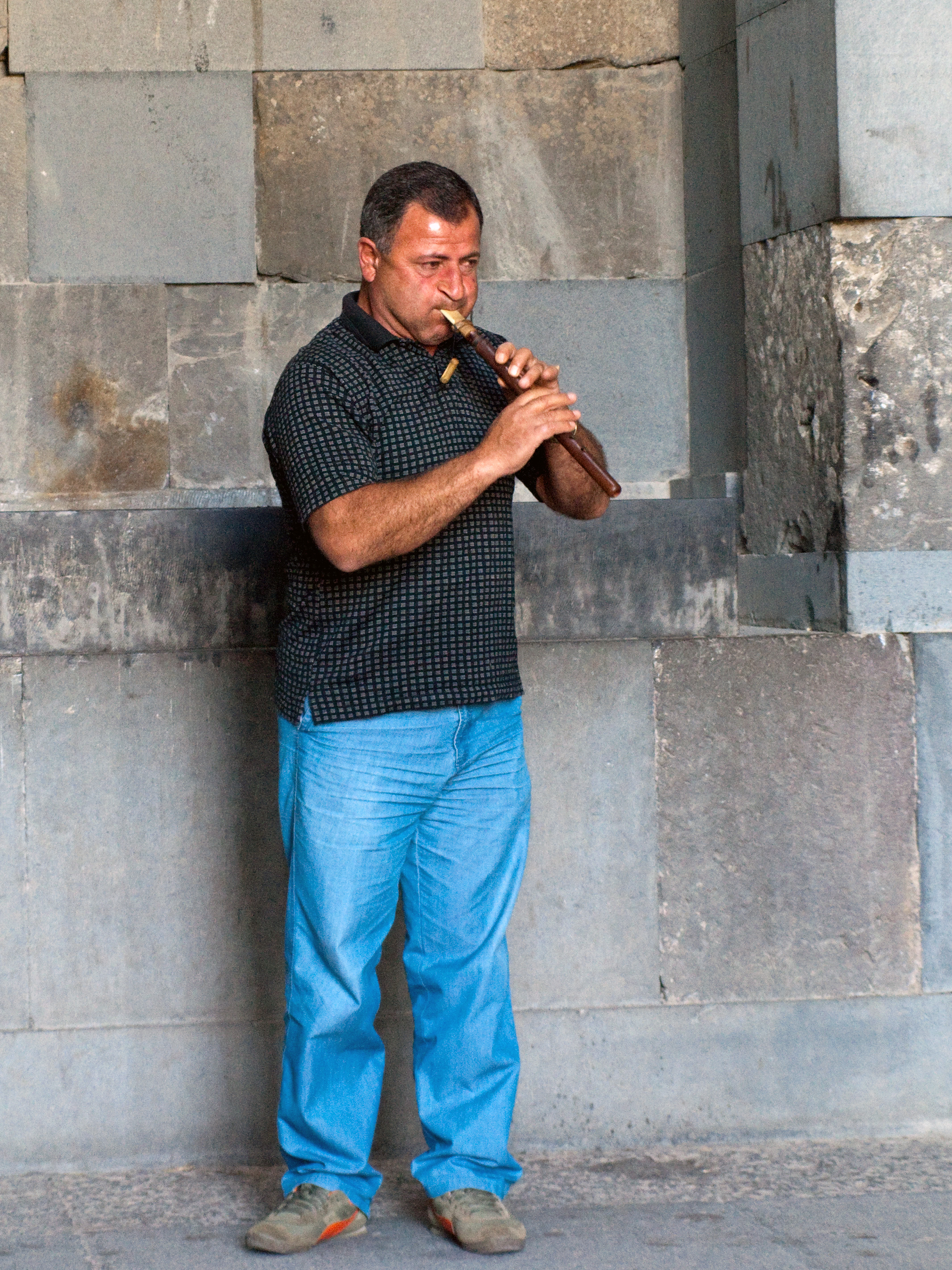 Voskan Vardanyan playing the duduk at Garni Temple, with the whole instrument and his hands visible