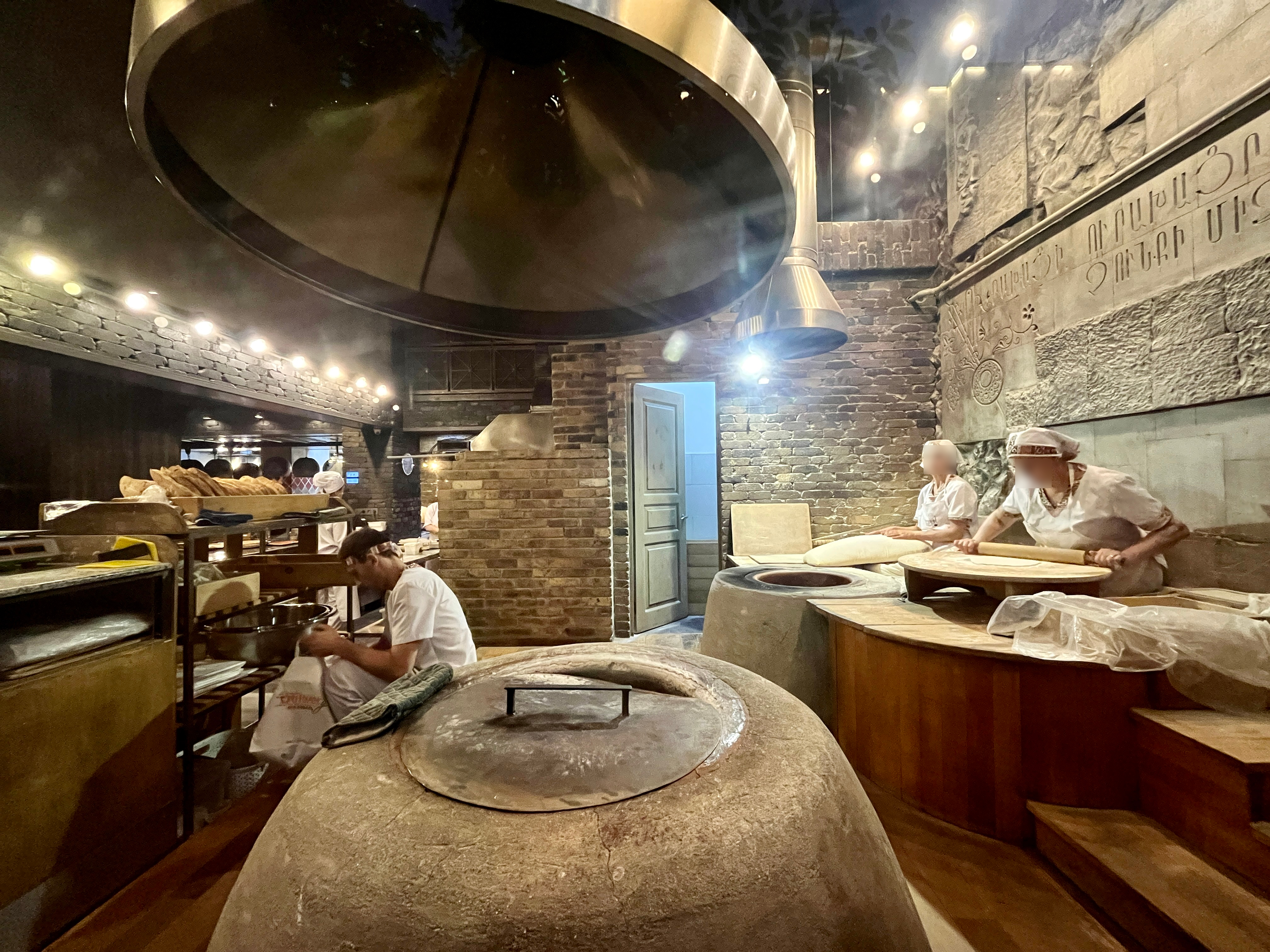 Bakers preparing lavash beside round ovens in a Yerevan restaurant
